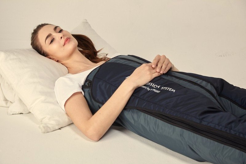 Kundin liegt entspannt in einem Kompressionsanzug zur apparativen Lymphdrainage
