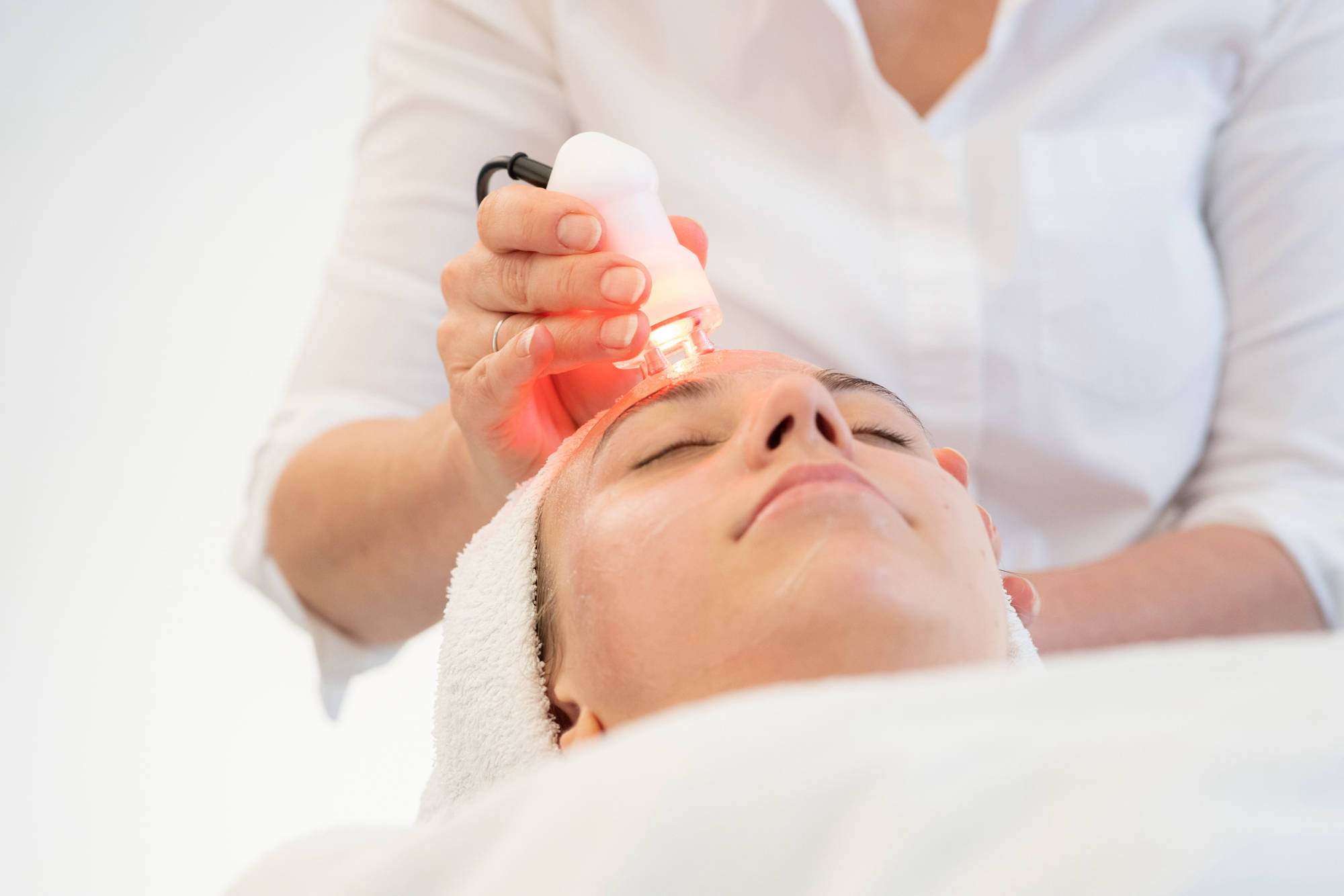 Anti-Age-Behandlung mit fourtec: Kosmetikerin führt das Gerät über die Stirn
